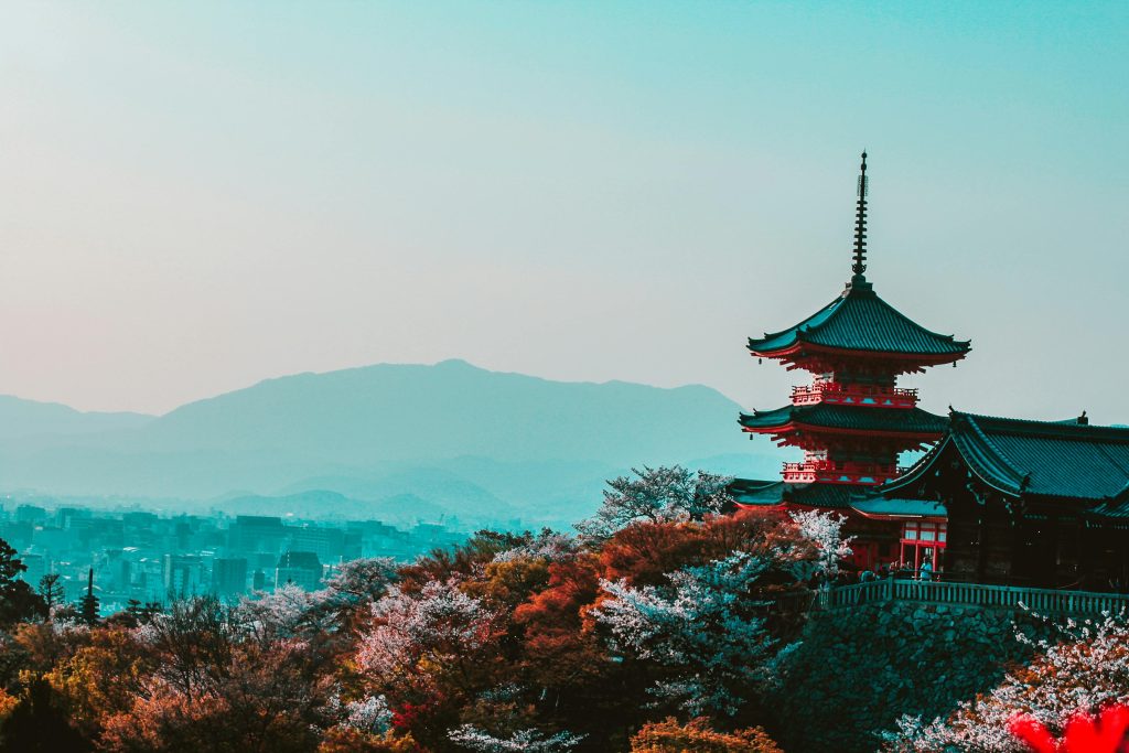 Scenic view of Kiyomizu-dera Temple with cherry blossoms in Kyoto, Japan, capturing traditional Japanese architecture at twilight.